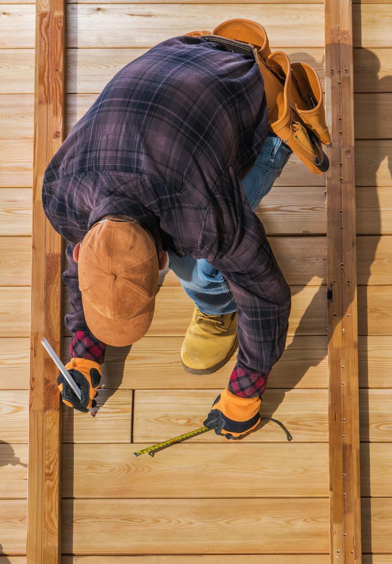 A carpenter measuring boards on a new wood deck
