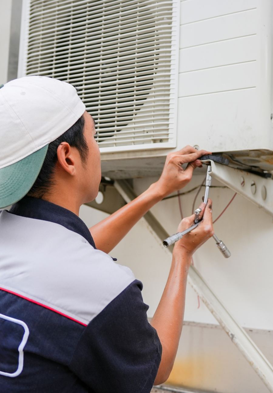 A technician working on an outdoor air conditioning unit